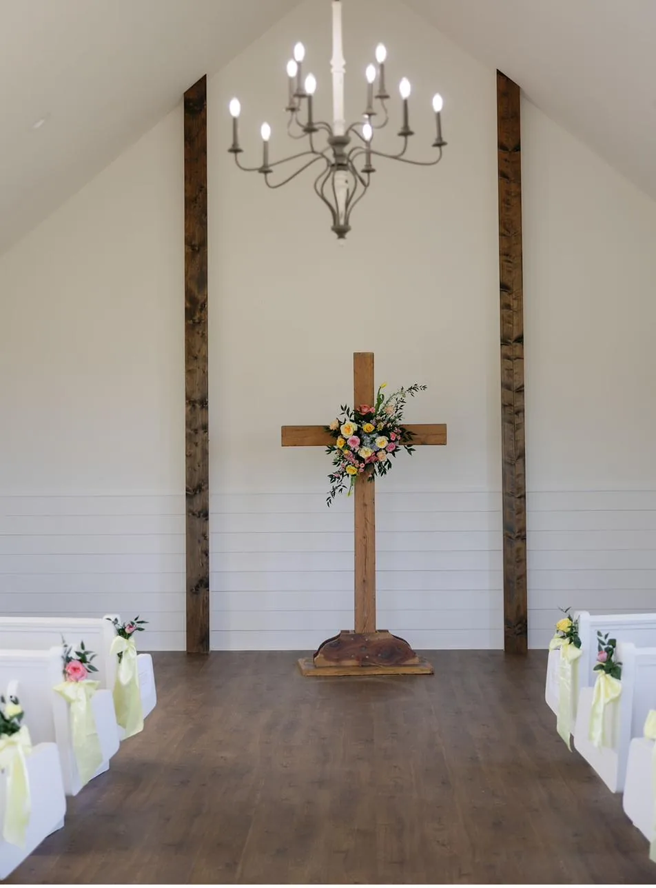 The white chapel altar with wooden cross and fresh florals at Gateley Hill Gardens