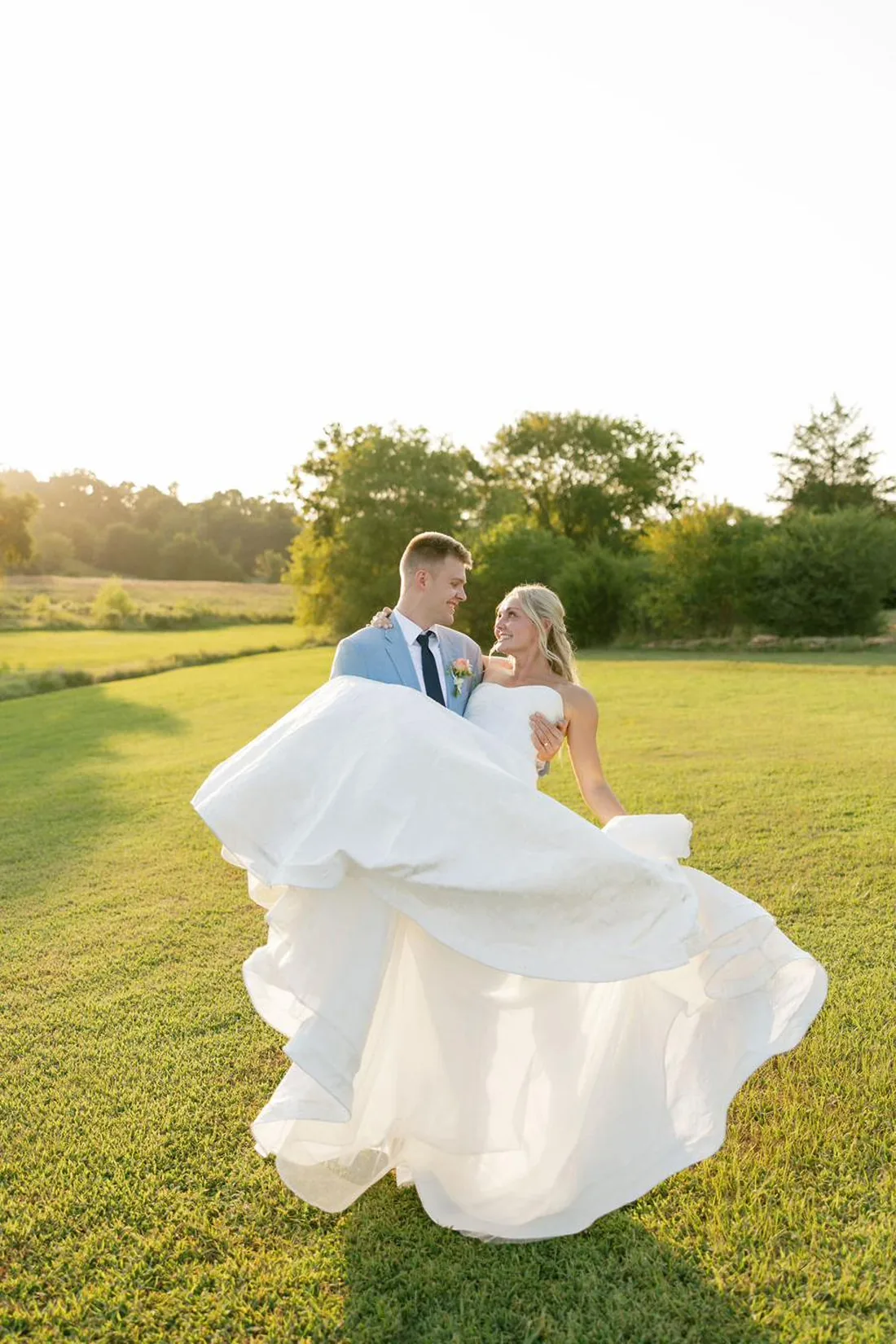 Groom lifting the bride in a golden field at sunset at Gateley Hill Gardens