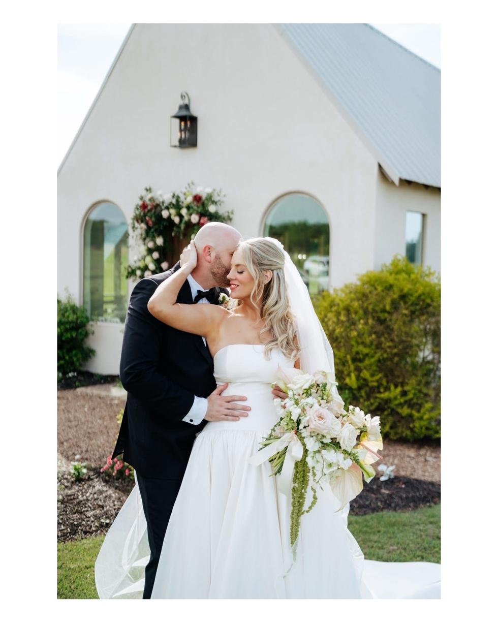 Bride and groom at the white stucco chapel at Gateley Hill Gardens